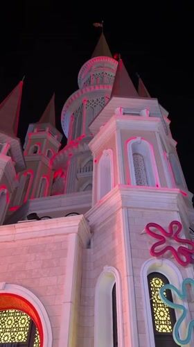 Crowds gather at a lit-up themed complex after dark