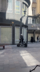 Man rides three-wheeled scooter in Budapest courtyard