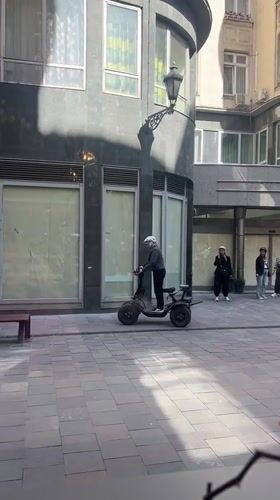 Man rides three-wheeled scooter in Budapest courtyard