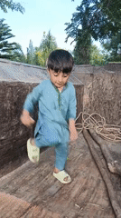 Child plays on tractor in Pakistani village yard