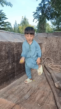 Child plays on tractor in Pakistani village yard