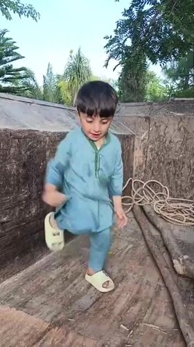 Child plays on tractor in Pakistani village yard