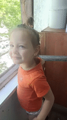 Young girl waves from window in Zaporizhzhia, Ukraine
