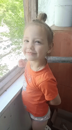 Young girl waves from window in Zaporizhzhia, Ukraine