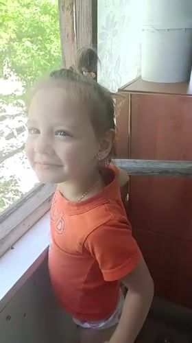 Young girl waves from window in Zaporizhzhia, Ukraine