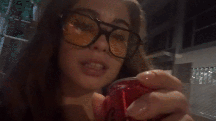 Woman drinks soda from red can in Hong Kong