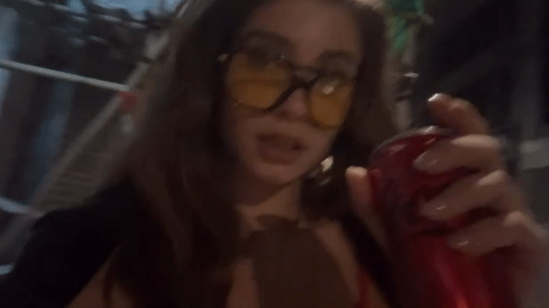 Woman drinks soda from red can in Hong Kong