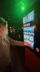 Woman browses music decades on digital jukebox at London bar