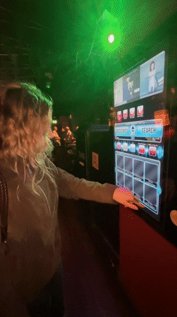 Woman browses music decades on digital jukebox at London bar