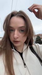 Woman photographed on Kragujevac street wearing white jacket, earphones