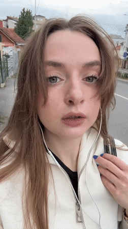 Woman photographed on Kragujevac street wearing white jacket, earphones