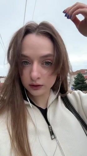 Woman photographed on Kragujevac street wearing white jacket, earphones