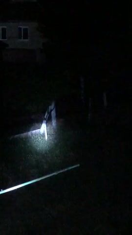This video captures a nighttime scene in Calfa, Moldova. The primary subject is a house, visible in the background, illuminated by a bright light, possibly a flashlight. The house appears to be two stories with several windows. The surrounding area is dark, with trees and foliage obscuring much of the detail.

The activity taking place seems to be exploration or observation of the house and its surroundings at night. The movement of the camera suggests someone is walking or driving, holding a light source that sweeps across the scene. The overall mood is mysterious and somewhat eerie due to the darkness and the isolated nature of the setting. The time of day is clearly night. There are no discernible weather conditions, but the darkness suggests clear skies or at least no heavy precipitation.

Notable details include the bright light source, which creates a strong contrast with the darkness, and the faint outlines of what might be other structures or objects in the distance. There are no visible text elements in the video. The location context of Calfa, Moldova, adds a specific geographical marker to this otherwise generalized nighttime rural scene.