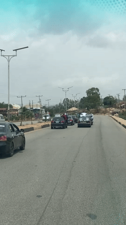 Woman stands on Mercedes roof during motorcade in Nigeria