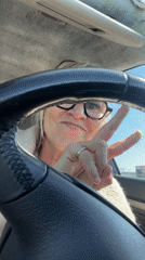 Woman makes peace sign gesture while seated in car