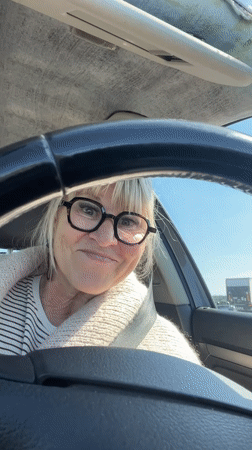 Woman makes peace sign gesture while seated in car