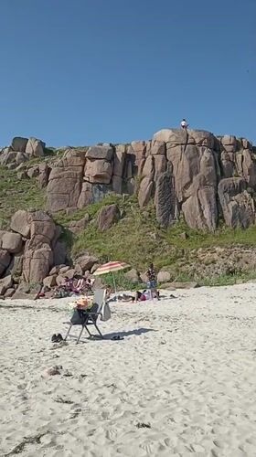 Sunny beach day at Carnboy with caravans, cliffs, and calm water