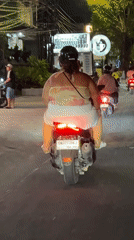 Woman rides moped at night in Kuta, Indonesia