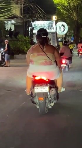 Woman rides moped at night in Kuta, Indonesia