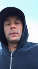 Man in hoodie walks Moscow bridge during evening hour