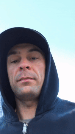 Man in hoodie walks Moscow bridge during evening hour