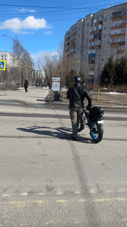 Motorcyclist signals on crosswalk with electric scooter in Surgut