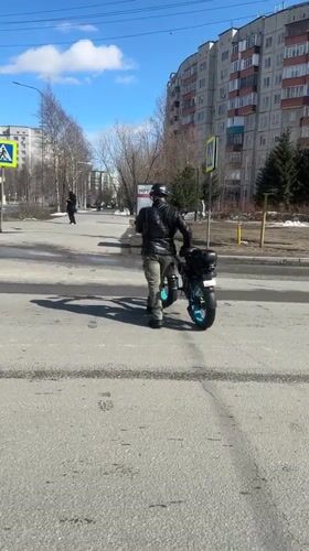 Motorcyclist signals on crosswalk with electric scooter in Surgut