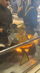 Kitchen staff prepare vegetables in commercial wok in Riga