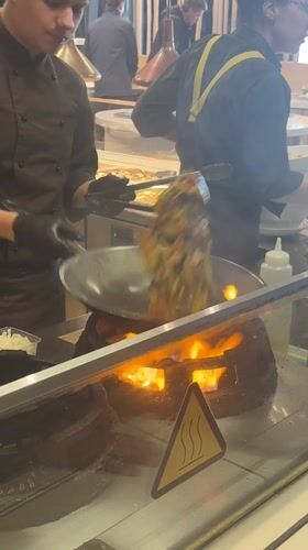 Kitchen staff prepare vegetables in commercial wok in Riga