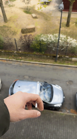 Person smoking cigarette overlooks Frankfurt playground and street scene