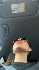 Woman in sunglasses looks up while sitting in car