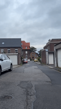 Quiet Krefeld street with parked cars and garden flowers
