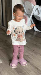 Toddler in Dalmatian shirt stands on wooden floor