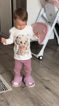 Toddler in Dalmatian shirt stands on wooden floor