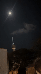 Full moon observed over illuminated tower in Pattaya