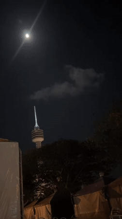 Full moon observed over illuminated tower in Pattaya