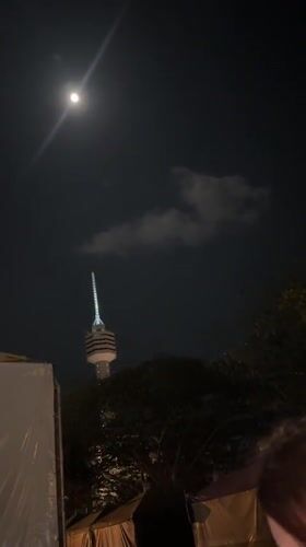 Full moon observed over illuminated tower in Pattaya