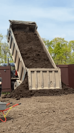 Dump truck delivers soil to garden area in Starokorsunskaya