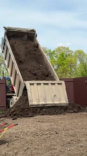 Dump truck delivers soil to garden area in Starokorsunskaya