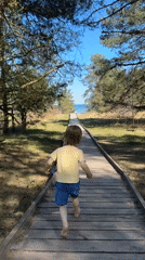 Child runs barefoot to ocean on boardwalk in Latvia
