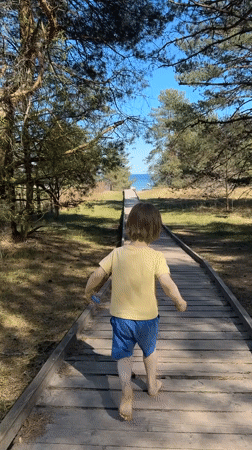 Child runs barefoot to ocean on boardwalk in Latvia
