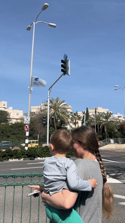 Woman and child wait at crosswalk in Kiryat Motzkin