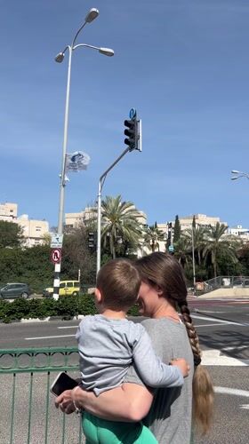 Woman and child wait at crosswalk in Kiryat Motzkin