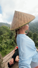 Three people relax on wooden platform overlooking Indonesian mountains