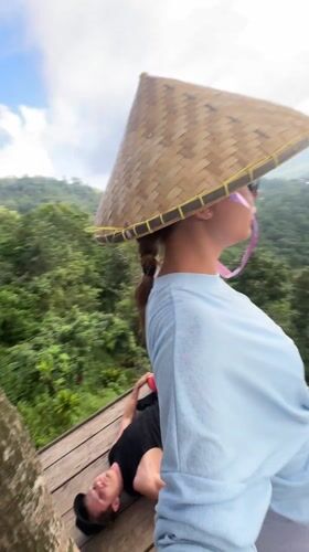 Three people relax on wooden platform overlooking Indonesian mountains