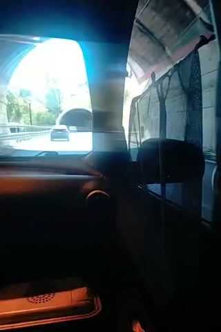The video shows the interior of a car driving on a road. Sunlight streams in from the left side. Outside the car, a tunnel is visible ahead, with other cars driving towards it. As the car enters the tunnel, the lighting changes to artificial. The dashboard of the car is visible, including an air vent and a cooler box. The view is from the passenger seat.
