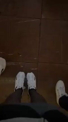 The video starts with a shot of three pairs of feet standing on a tile floor. The camera then moves forward, following the person wearing white sneakers. As they walk, other people can be seen walking on the same floor. Eventually, the camera angle changes to show the backs of a group of people looking at the interior of a building. The building has ornate decorations and artwork, particularly a large altar, suggesting it is a church.