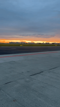Golden sunset over Warsaw airport, seen from tarmac and wing