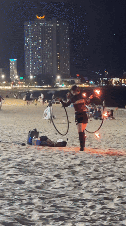 Fire hoop performer practices acrobatics on Nha Trang beach