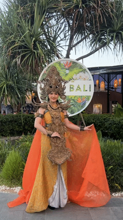 Woman poses in traditional Balinese costume at Denpasar sign